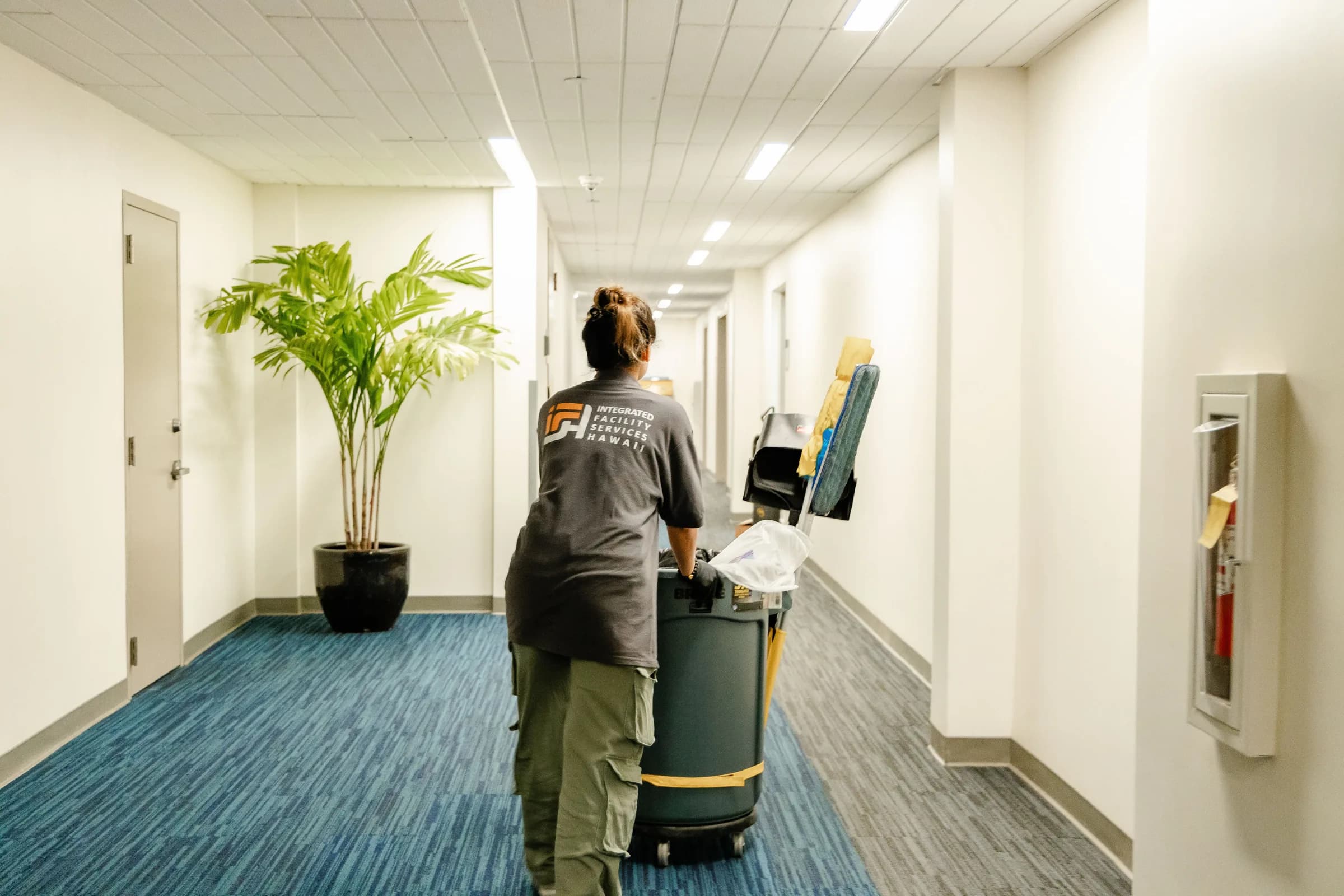 IFSH team member moving a janitorial cart through a facility corridor